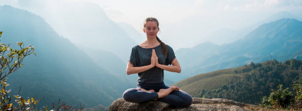 Young lady meditating in lotus position, doing yoga exercises in morning, relaxing and making practices to get positive thinking